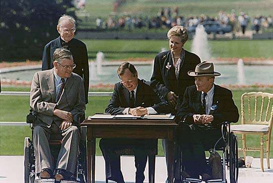 President George H. W. Bush signs the Americans with Disabilities Act on July 26, 1990, joined by disability advocates