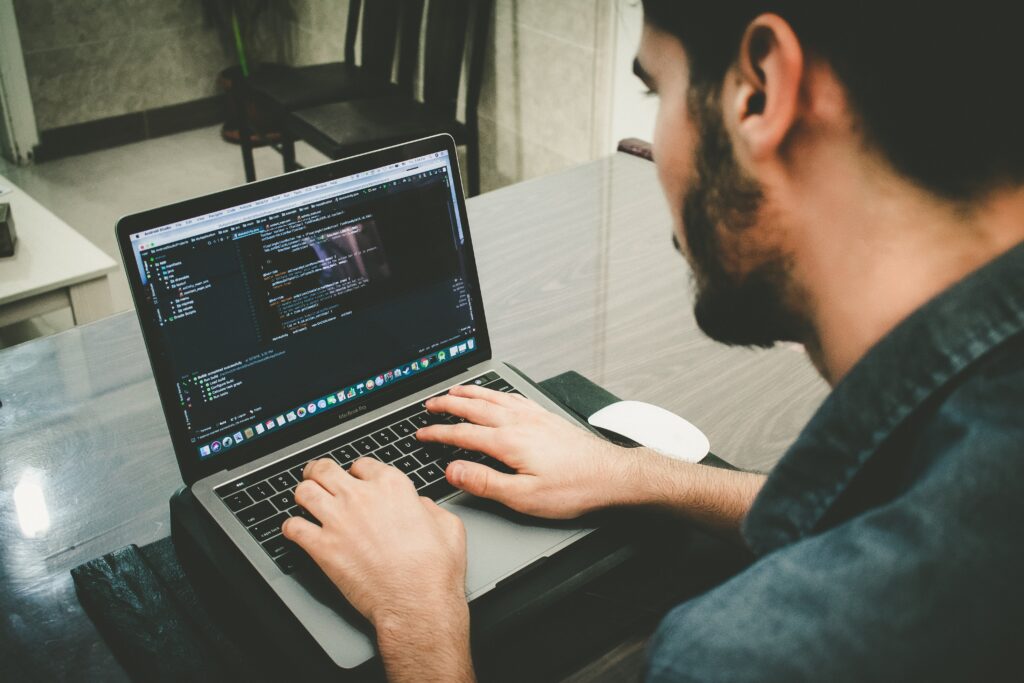 Developer typing on a MacBook with a code editor open on screen