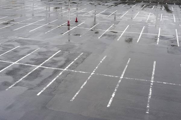 Empty parking lot with white-striped parking spaces on wet asphalt
