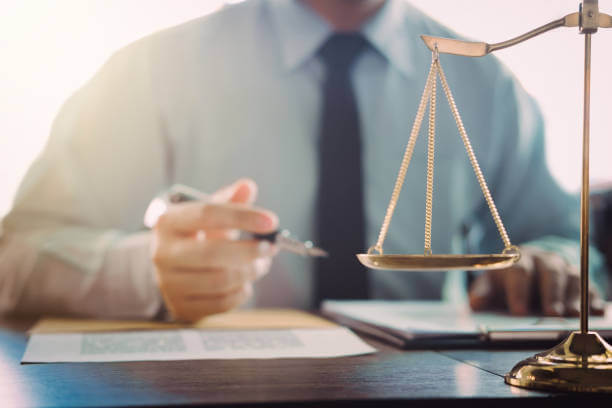 Attorney at a desk with a brass scale of justice, reviewing legal documents
