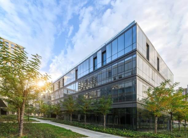Modern glass-fronted commercial office building surrounded by trees